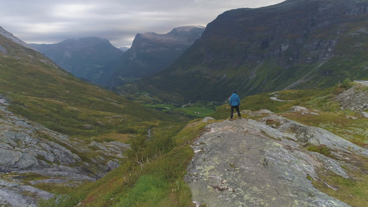 男人在夏季或秋季站在挪威的山谷中鸟瞰图无人机绕着人视频