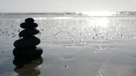 在海洋海滩上平衡岩石在海浪中堆叠石头沙滩上的碎石金字塔视频