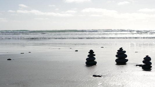 在海洋海滩上平衡岩石在海浪中堆叠石头沙滩上的碎石金字塔视频