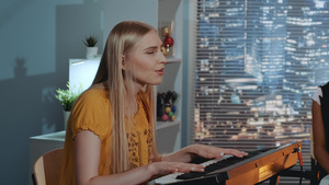 在家庭录音室排练乐队时唱着一首歌并演奏键盘的金发女歌16秒视频