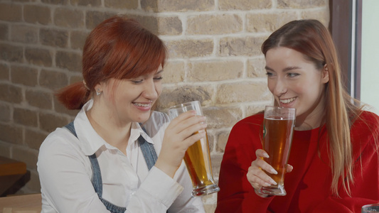 有两个年轻女子在酒吧一起欢庆喝着啤酒杯的酒杯视频