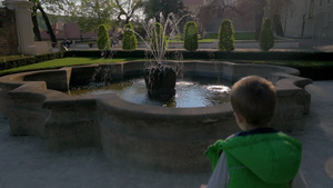 小男孩跑向喷泉扔硬币到喷泉中16秒视频