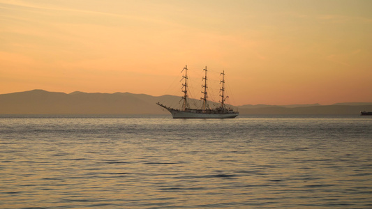 日落背景下有一艘帆船的海景视频