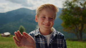微笑的男孩在绿色草地上挥手13秒视频