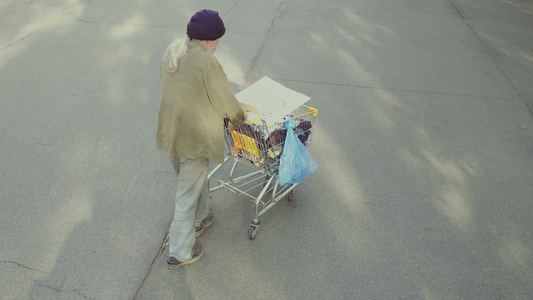 流浪老人在街上推着购物车靠近长凳于是视频
