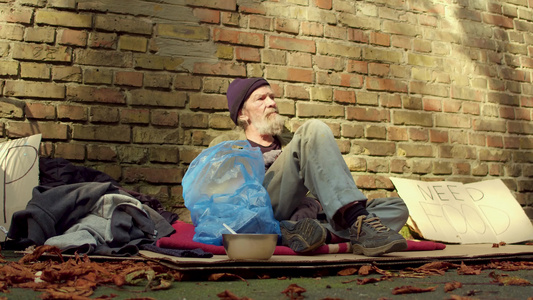 在墙砖边的纸板上坐着无家可归的人视频