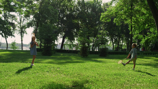 几个兄弟姐妹在绿色公园里聊天打羽毛球视频