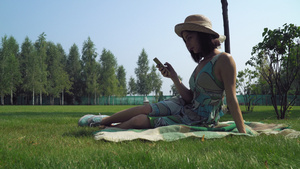 黑发姑娘坐在公园的毯子上在电话里收到一条信息笑声13秒视频