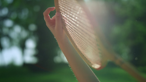 特写手拿着木制羽毛球拍在公园的金色阳光下10秒视频