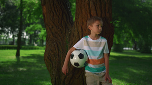 小男孩抱着足球靠在树上19秒视频
