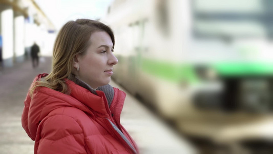 年轻女子站在站台平台上等待她的火车视频
