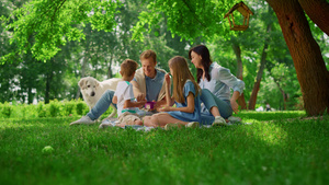 幸福的家庭在周末野餐时喂白狗30秒视频