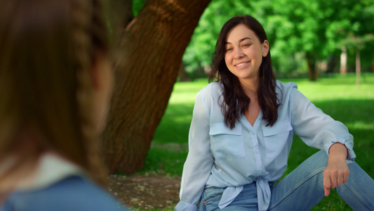 微笑的女人坐在公园特写镜头的草地上视频