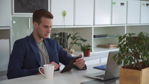 现代办公室的英俊商人在触摸平板电脑上读邮件19秒视频