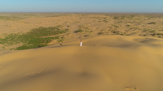 穿着白裙子长发的孤单年轻女子在沙漠中的沙滩上举起手来视频