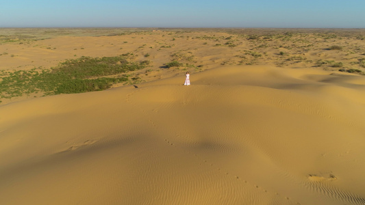 身着白裙子长发的孤单年轻女子仍停留在沙漠沙滩上无人驾驶视频