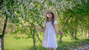 年轻女孩在阳光明媚的春日享受开花的果园19秒视频
