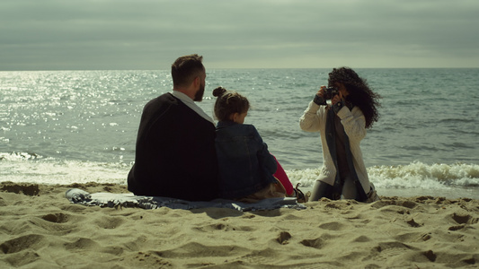 在晴天海滩拍照的年轻家庭视频