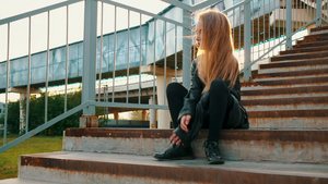 穿着黑色皮夹克的年轻女孩坐在楼梯上摆在楼梯上的时装模特12秒视频