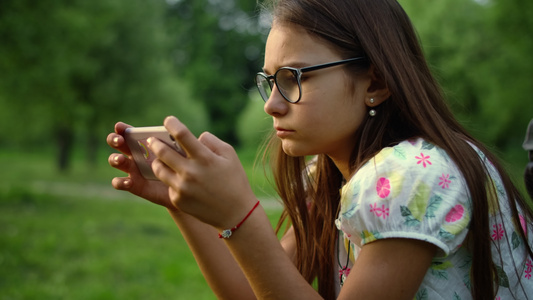 女孩在绿林里拿着手机上发短信视频