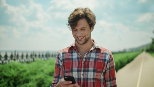在外面使用智能手机的快乐男人 在公园路上走着笑的人视频