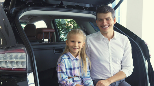 可爱的父亲和女儿坐在开着的车后备箱上视频