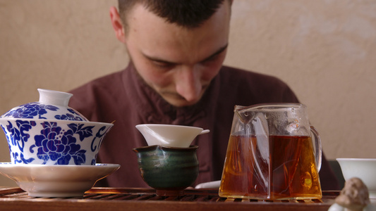 年轻人在东方餐厅喝茶时使用手机大师通过智能手机在茶几视频