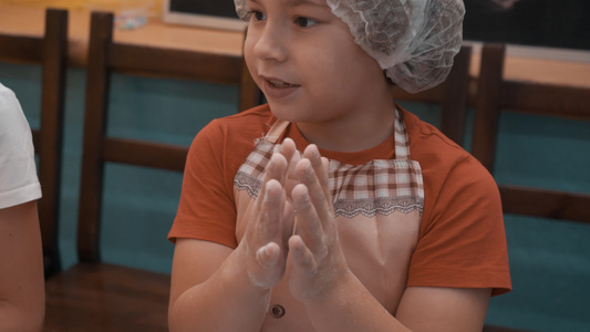 小男孩在烹饪课上滚面团前用面粉搓手小男孩厨师在学校视频