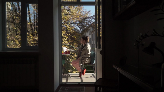 年轻白人女子在阳光明媚的秋天在露天阳台上准备茶杯视频