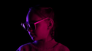戴着墨镜的微笑少女在霓虹灯照明的黑暗工作室里看着相机11秒视频