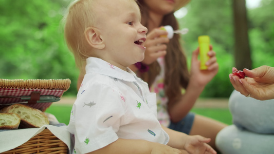 与森林中的母亲和姐妹坐在毯子上笑着的幼儿视频