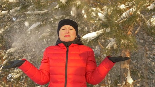 幸福的女士站在雪花下从雪树下在冬季森林中慢动视频