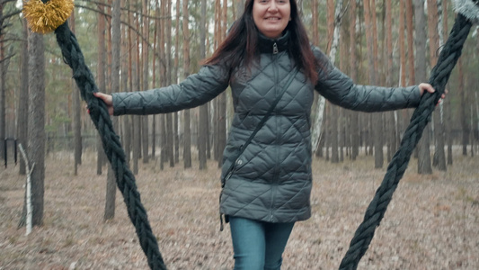 幸福的女人微笑着在秋天的森林里荡秋千性格开朗的女人视频