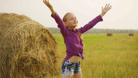 快乐的女孩在干草堆背景上向天空伸出手来少女在农村收获视频