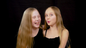 两个快乐的少女玩得开心同时在黑暗工作室装扮黑色背景29秒视频