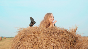 快乐的女孩躺在收割场的干草堆上快乐的少女在乡村田野16秒视频