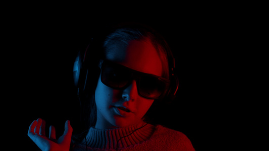 戴着耳机和墨镜的快乐女孩在黑暗中歌唱视频