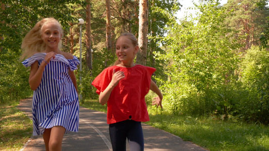 欢笑的女朋友在人行道上奔跑在夏季城市阳光明媚的公园视频