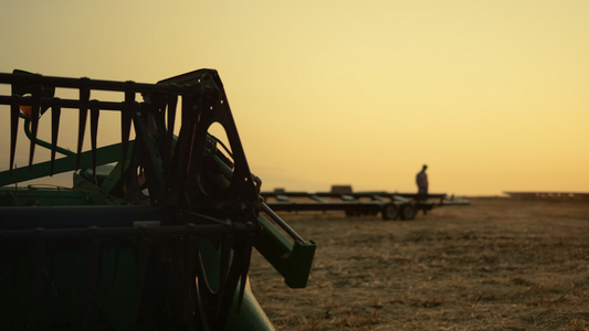 在金色的日落时间在麦田收获设备的农民剪影视频