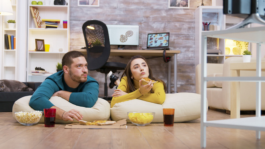 坐在枕头上吃披萨的一对愉快的caucasians情侣视频