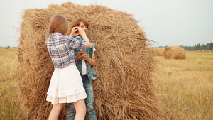快乐的男孩女孩在田野干草堆上玩15秒视频