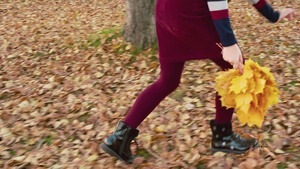 快乐的女孩从城市公园的落叶上捡到秋花花束17秒视频