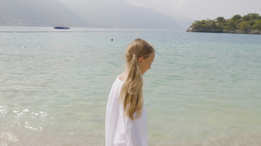 快乐的少女穿着白色衣服走在海边旅游女孩在夏日海滩的视频