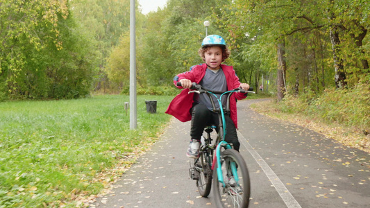 快乐的少年男孩在秋季公园骑自行车骑自行车的男孩在城市公园视频