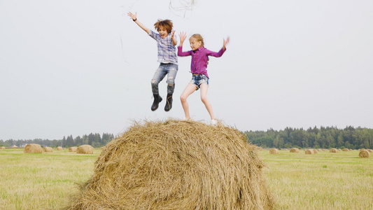 快乐的青少年在干草堆上吐干稻草无忧无虑的男孩和女孩视频