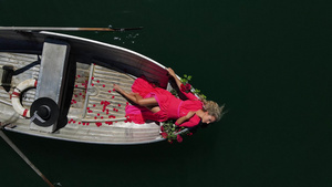 穿着红裙子的漂亮女人长着金发长头发在瑞士山湖上坐船9秒视频