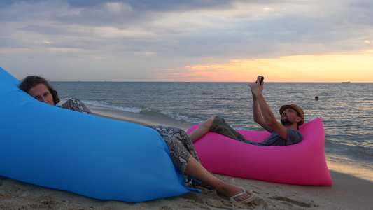一对夫妇在日出时坐在海滩上的气垫床上男人和女人在度假视频