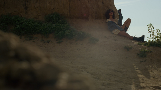轻松的女人靠在海边放松的沙崖视频