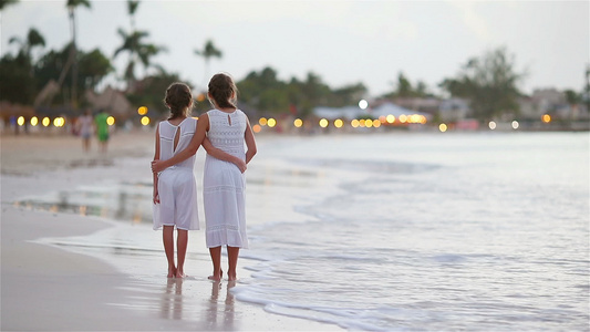 可爱的小孩在沙滩上走在美丽多彩的夕阳下视频