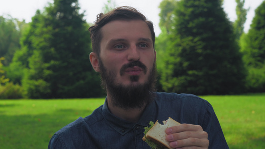 一个年轻人在公园里吃三明治配沙拉视频
